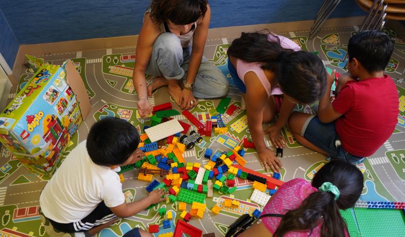 Un grupo de niños en situación de vulnerabilidad juegan en uno de nuestros centros junto a una monitora.