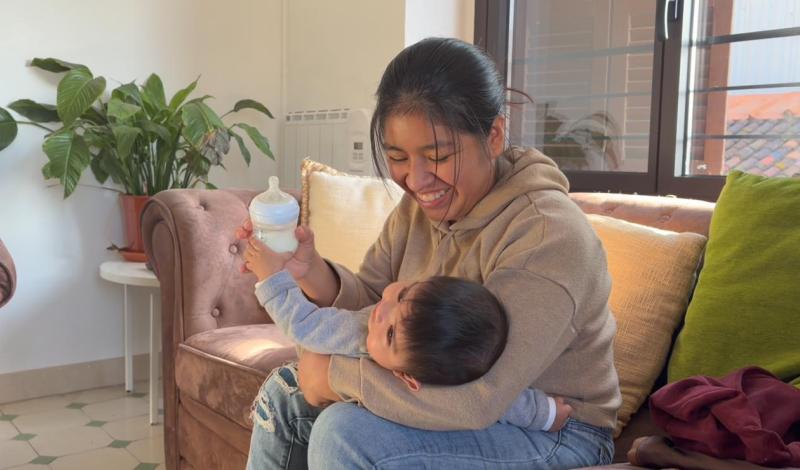 Una mujer sonríe mientras le da el biberón a su bebé