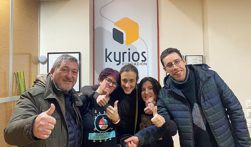 Grupo de cuatro personas con caras sonrientes y con los pulgares hacia arriba, en signo de optimismo y ánimo. Detrás de ellos, aparece el logo de la Fundación Kyrios.