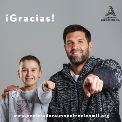 Felipe Reyes (ex jugador de baloncesto) junto a un niño sonríen y señalan al observador de la foto, se lee ¡ Graicas! y Aceleradora Unoentrecienmil debajo de una A mayúscula de colores, y en la parte inferior de la foto la web www.aceleradoraunoentrecienmil.org
