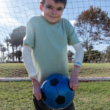 Foto de Leo en un campo de fútbol sosteniendo su balón.