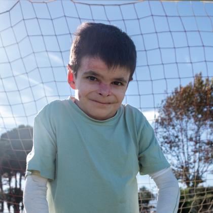 Foto de Leo en un campo de fútbol sosteniendo su balón.