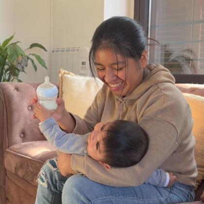 Una mujer sonríe mientras le da el biberón a su bebé