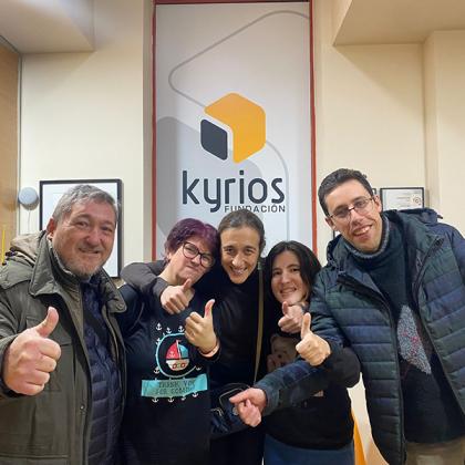 Grupo de cuatro personas con caras sonrientes y con los pulgares hacia arriba, en signo de optimismo y ánimo. Detrás de ellos, aparece el logo de la Fundación Kyrios.
